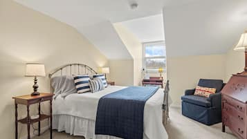 A bedroom with a bed, a chair, a dresser, and a lamp.