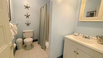 Un baño con inodoro, lavabo y cortina de ducha.