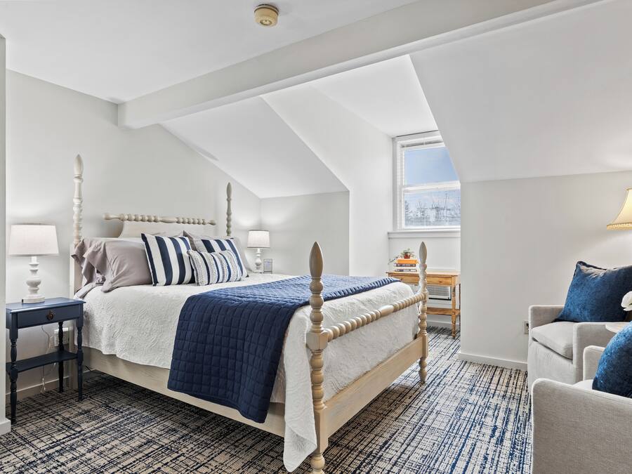 A bedroom with a bed, bedside tables, a chair, and a window.