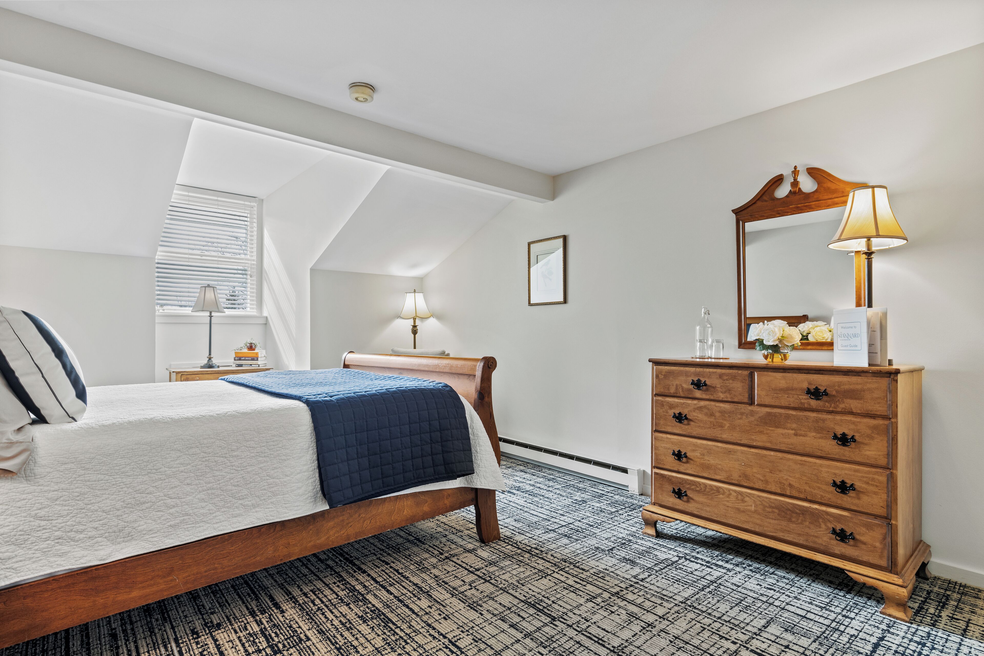 A bedroom with a bed, dresser, and a skylight.