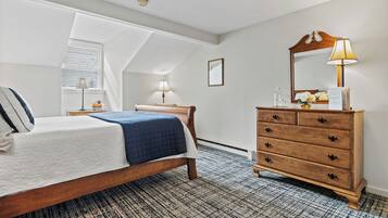 A bedroom with a bed, dresser, and a skylight.
