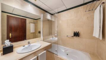 A bathroom with a large mirror, two sinks, a bathtub, and a towel rack.