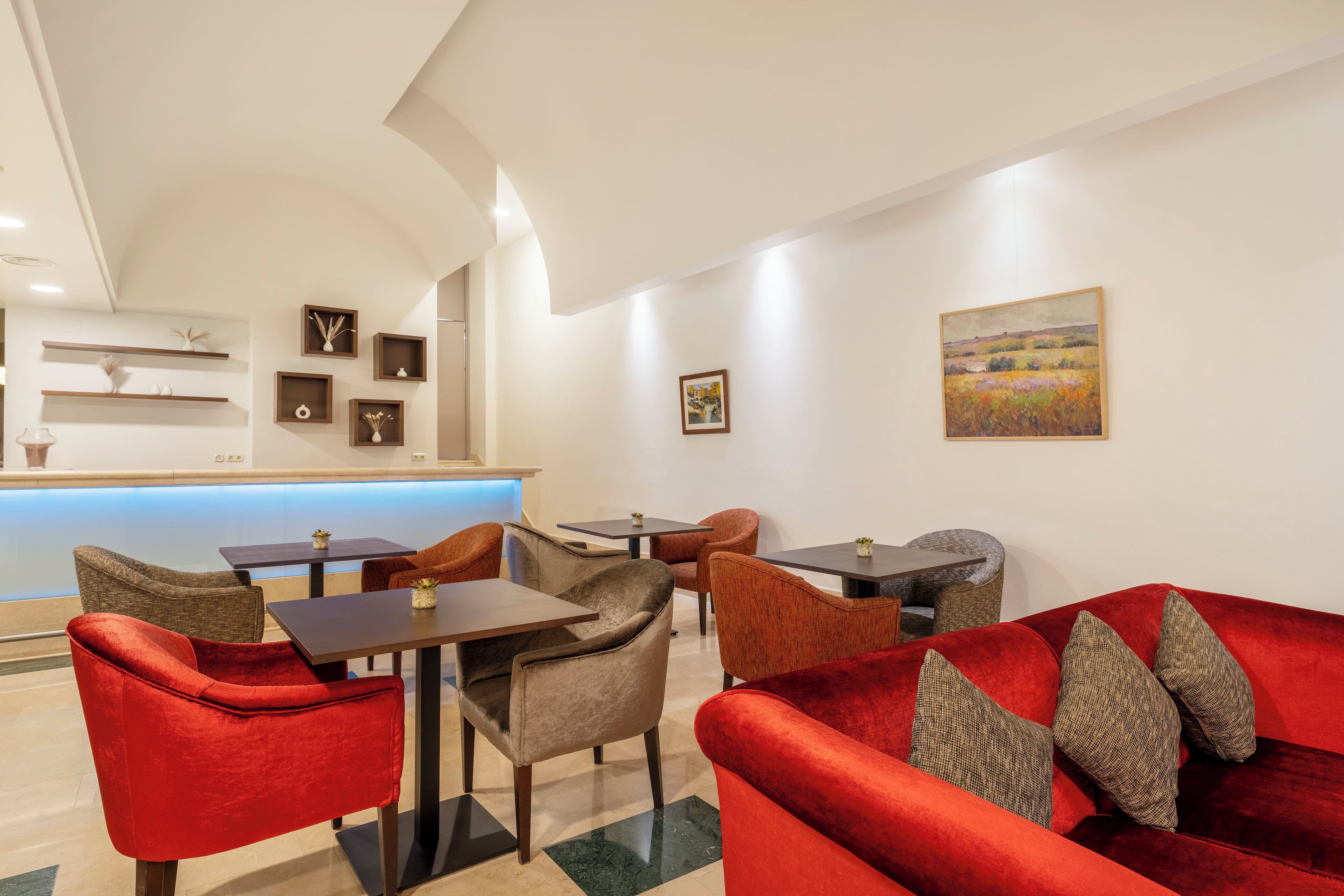 A modern hotel lobby with a reception desk, seating area, and artwork on the walls.