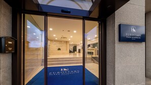 Ein Hotel Eingang mit einer Glastür, einem blauen Teppich und einem Schild mit dem Namen 'Eurostars Plaza Acueducto'.