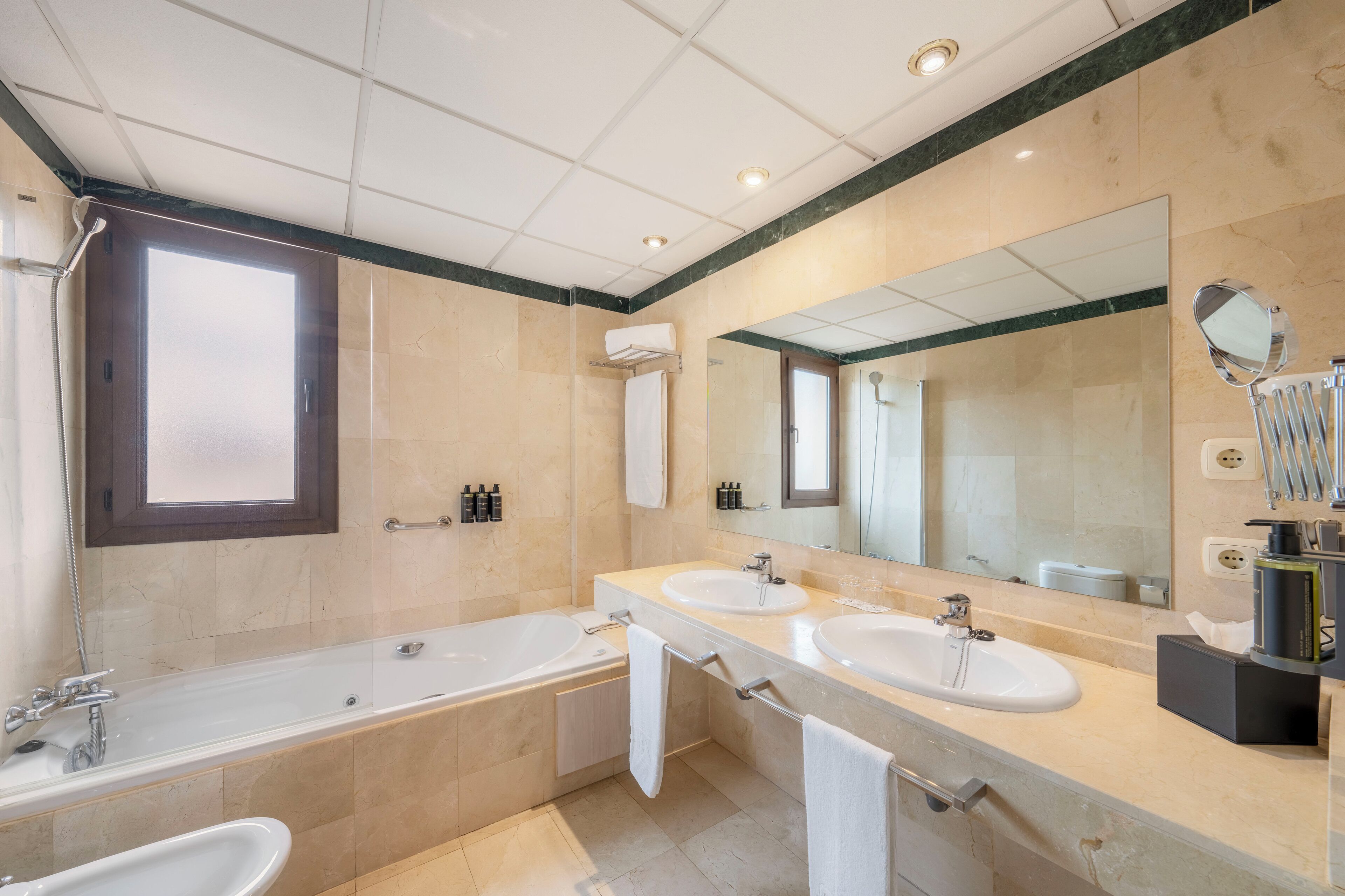 A modern bathroom with two sinks, a bathtub, and a large mirror.