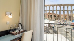 Une chambre d’hôtel avec vue sur un ancien aqueduc et une place animée.