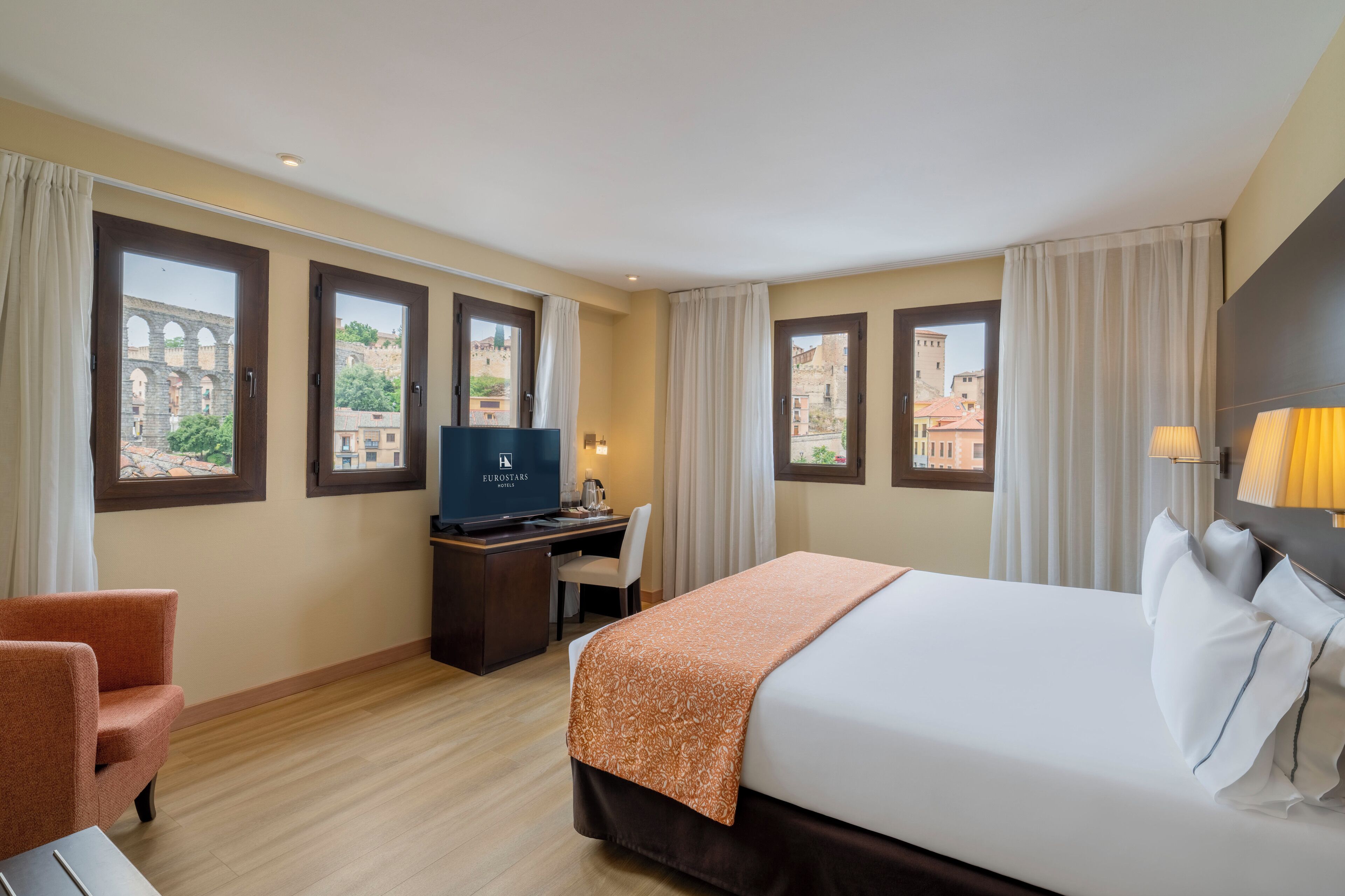 Une chambre d’hôtel avec un lit, un bureau, une chaise et des rideaux.