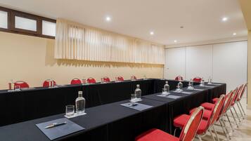 A conference room with a long table, red chairs, and water bottles.