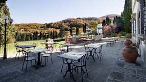 Un patio al aire libre con mesas y sillas, con vistas a un paisaje pintoresco de árboles y colinas.