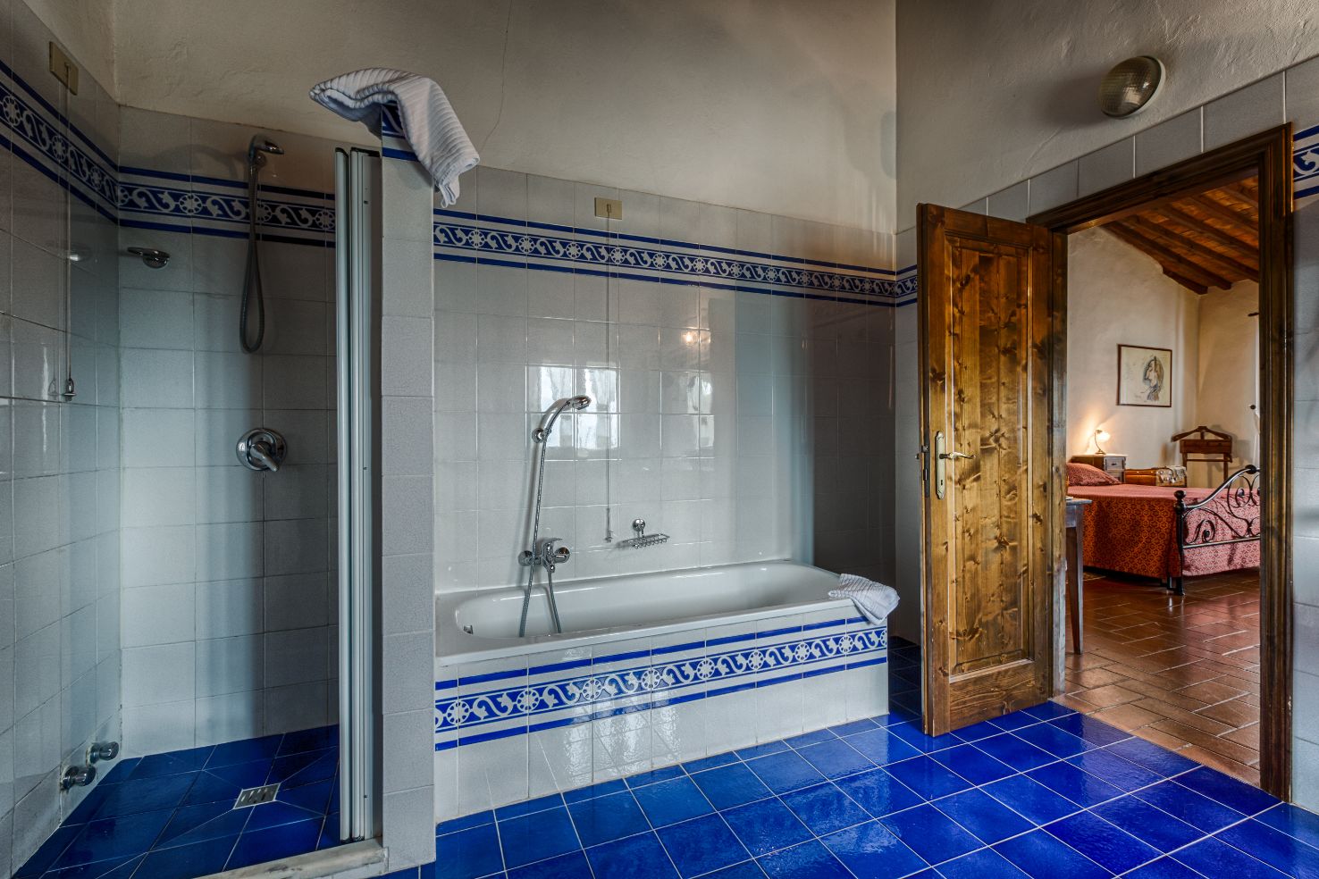 Un baño con bañera, ducha y piso de azulejos azules.