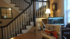 A home office with a desk, papers, a computer, and a staircase.