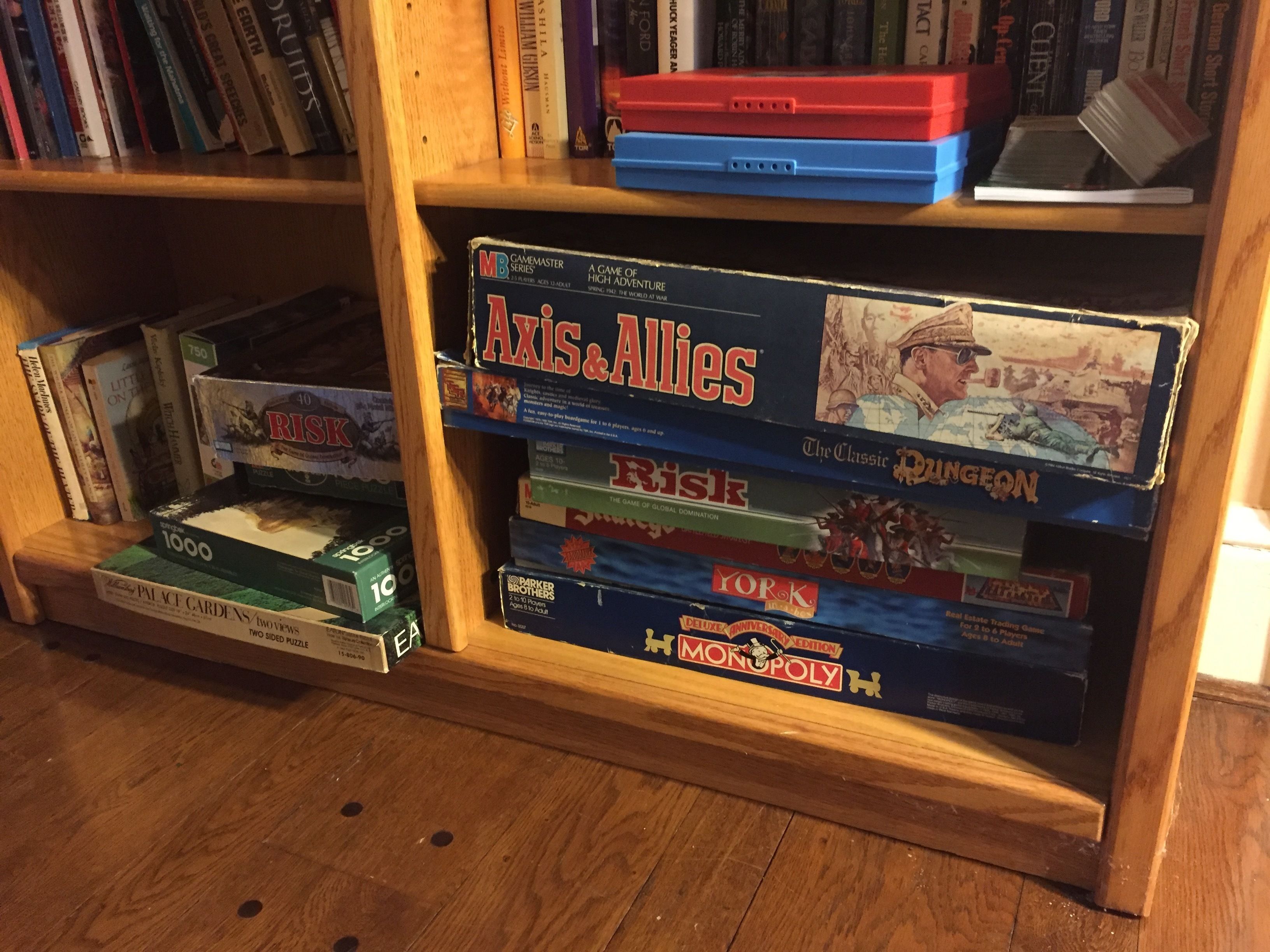 A bookshelf with various board games including Axis & Allies, Risk, and Monopoly.