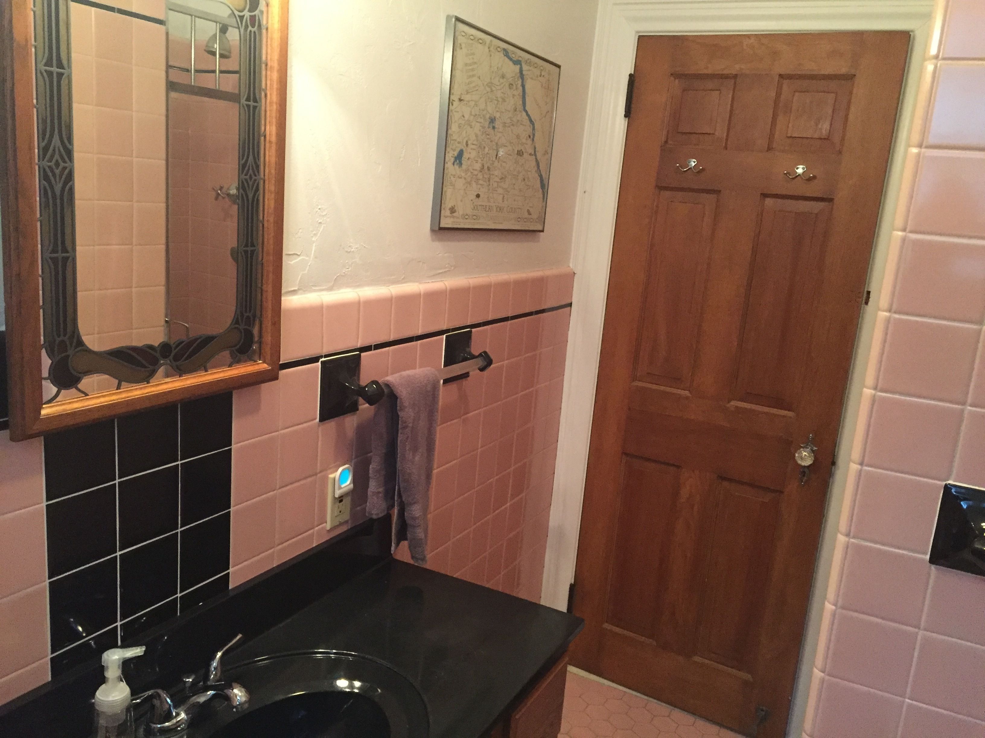 Ein Badezimmer mit einem schwarzen Waschbecken, einem Spiegel, einer Karte an der Wand und einer Holztür.