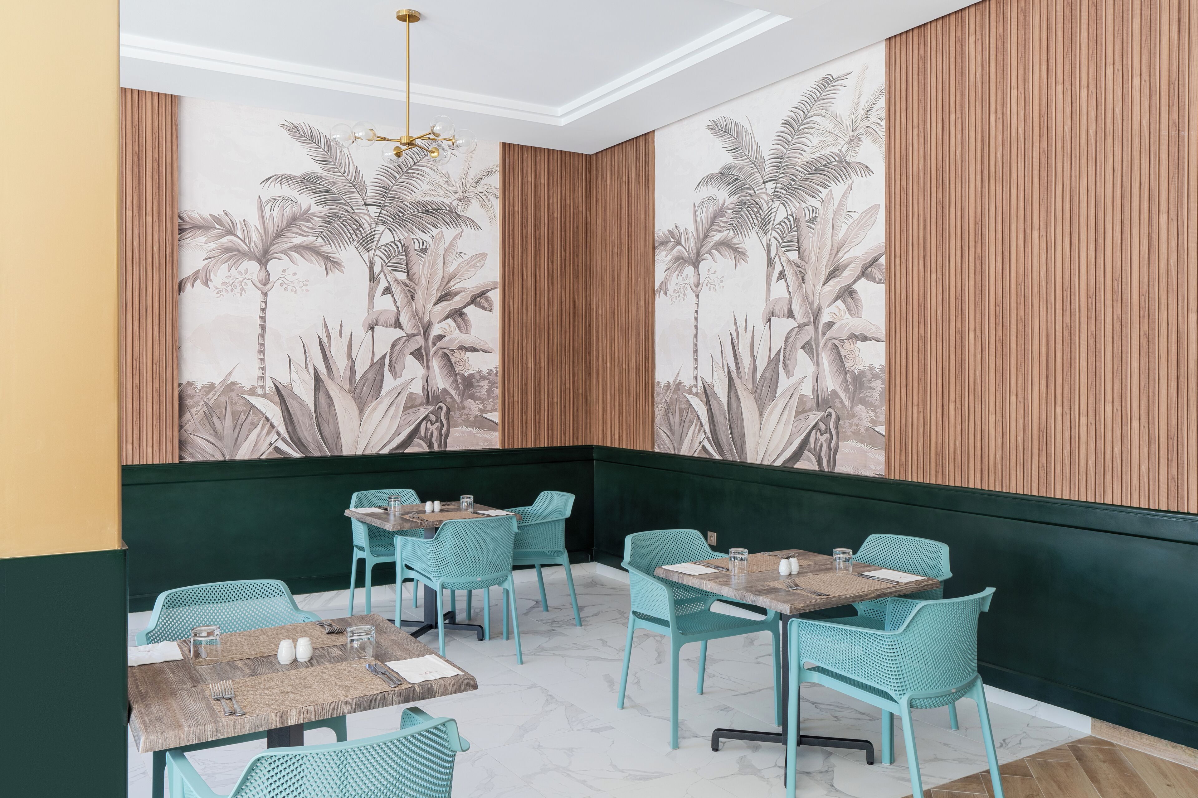 A restaurant interior with wooden panel walls, green upholstered booths, and a tropical mural.