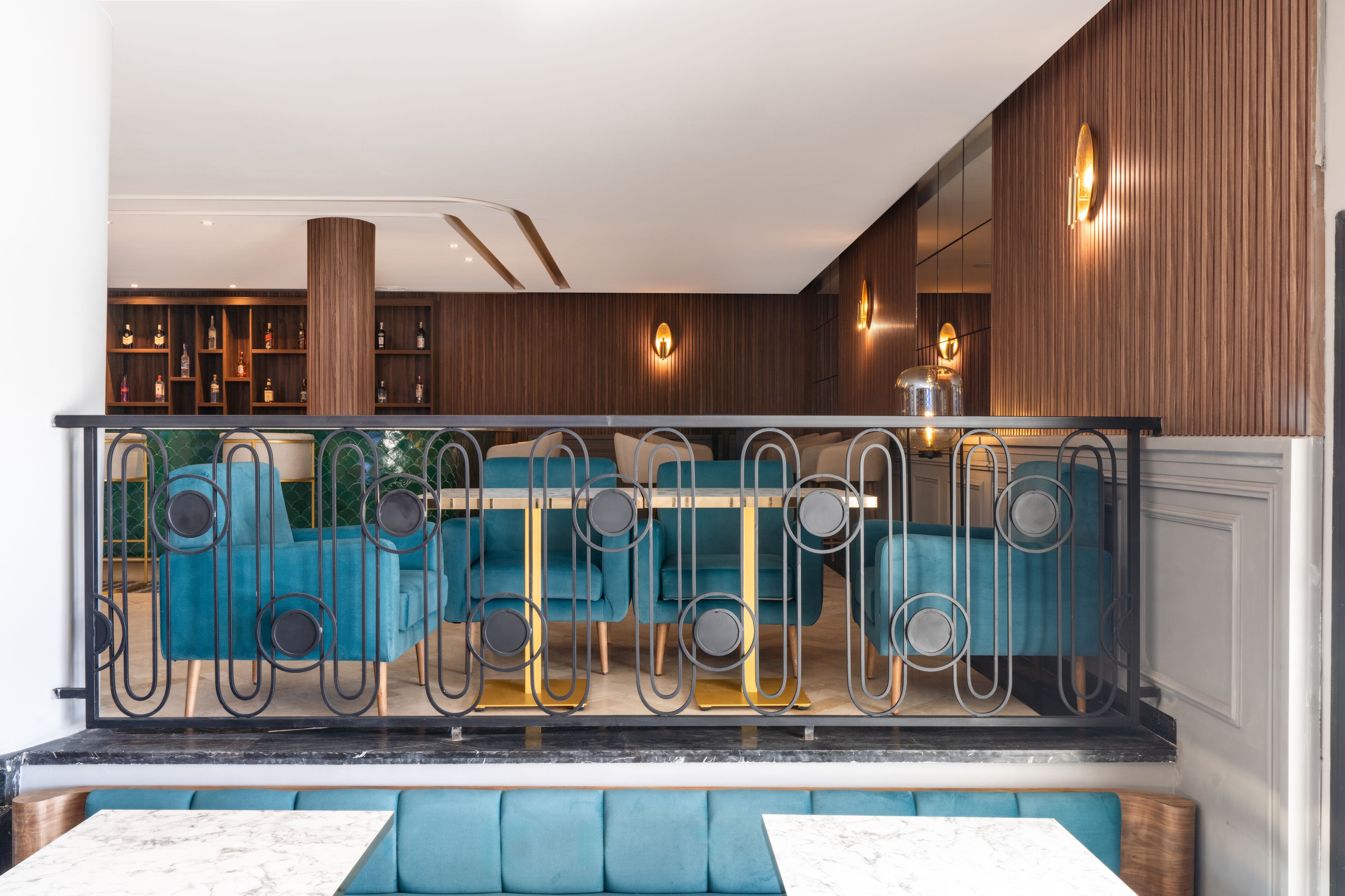 A modern interior with a bar area, seating with a metal railing, and wooden paneling.