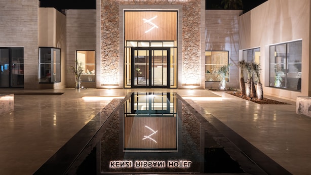 The exterior of Kenzi Rissani Hotel with a modern design, featuring a stone facade, large glass entrance, and a reflective water feature in front. - Kenzi Rissani Hotel (Errachidia)