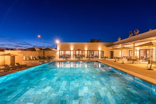 Una piscina al aire libre, sombrillas, sillones reclinables de piscina