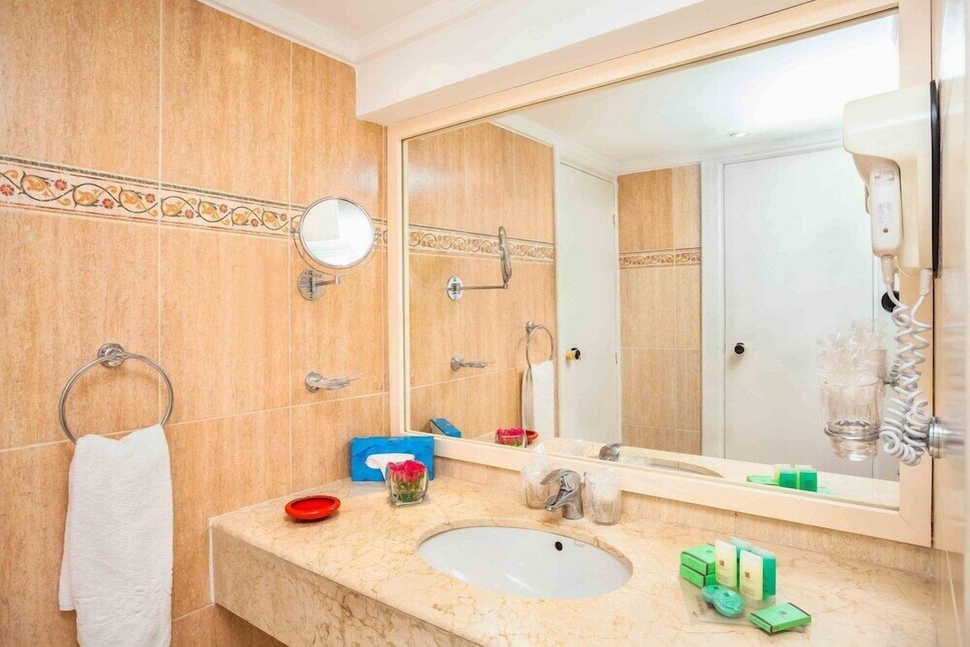 A bathroom with a sink, mirror, towel rack, and toiletries.