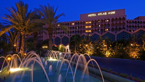 A hotel with a prominent sign reading "HOTEL ATLAS ASNI" and a fountain in the foreground. - Atlas Asni (Marrakech)
