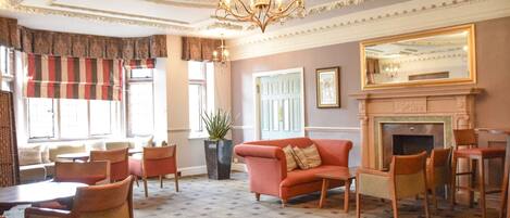 A spacious living room with a fireplace, comfortable seating, and a chandelier.