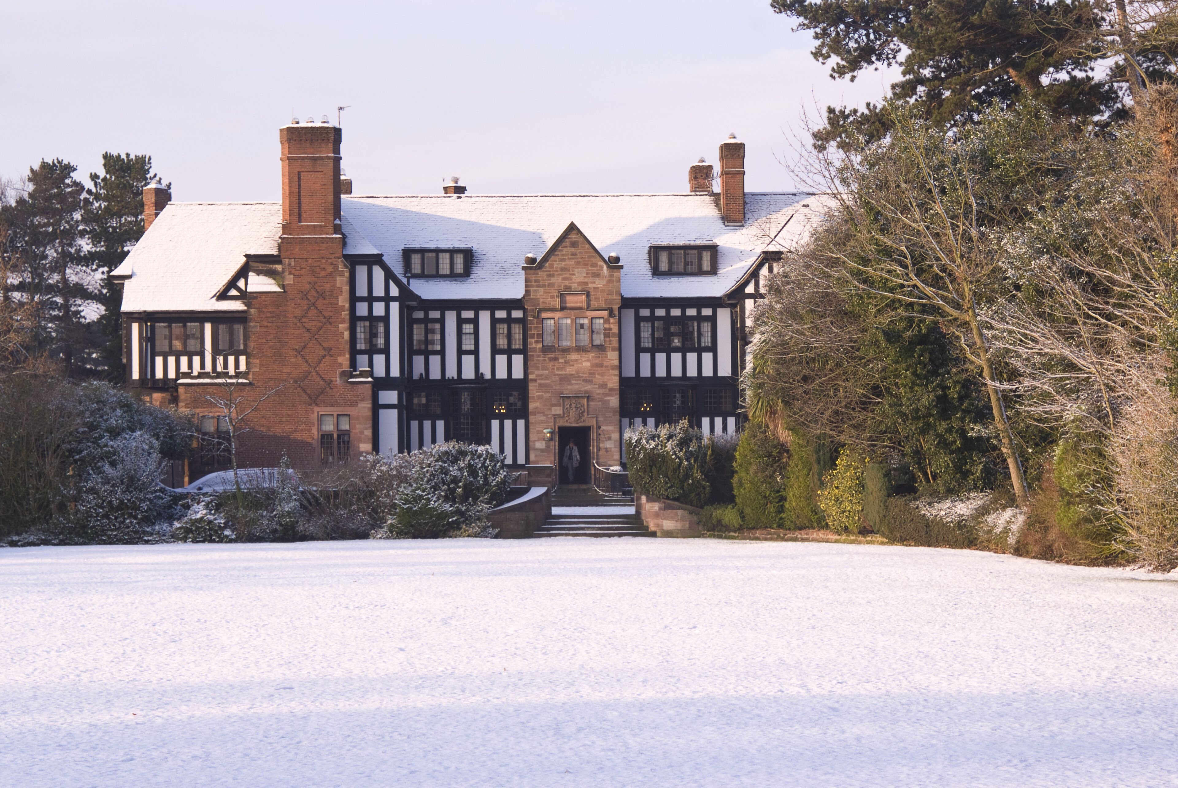 A large, historic building with a symmetrical facade, multiple chimneys, and a snow-covered roof.