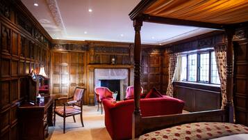 A traditional bedroom with a four-poster bed, a fireplace, and a large window with curtains.