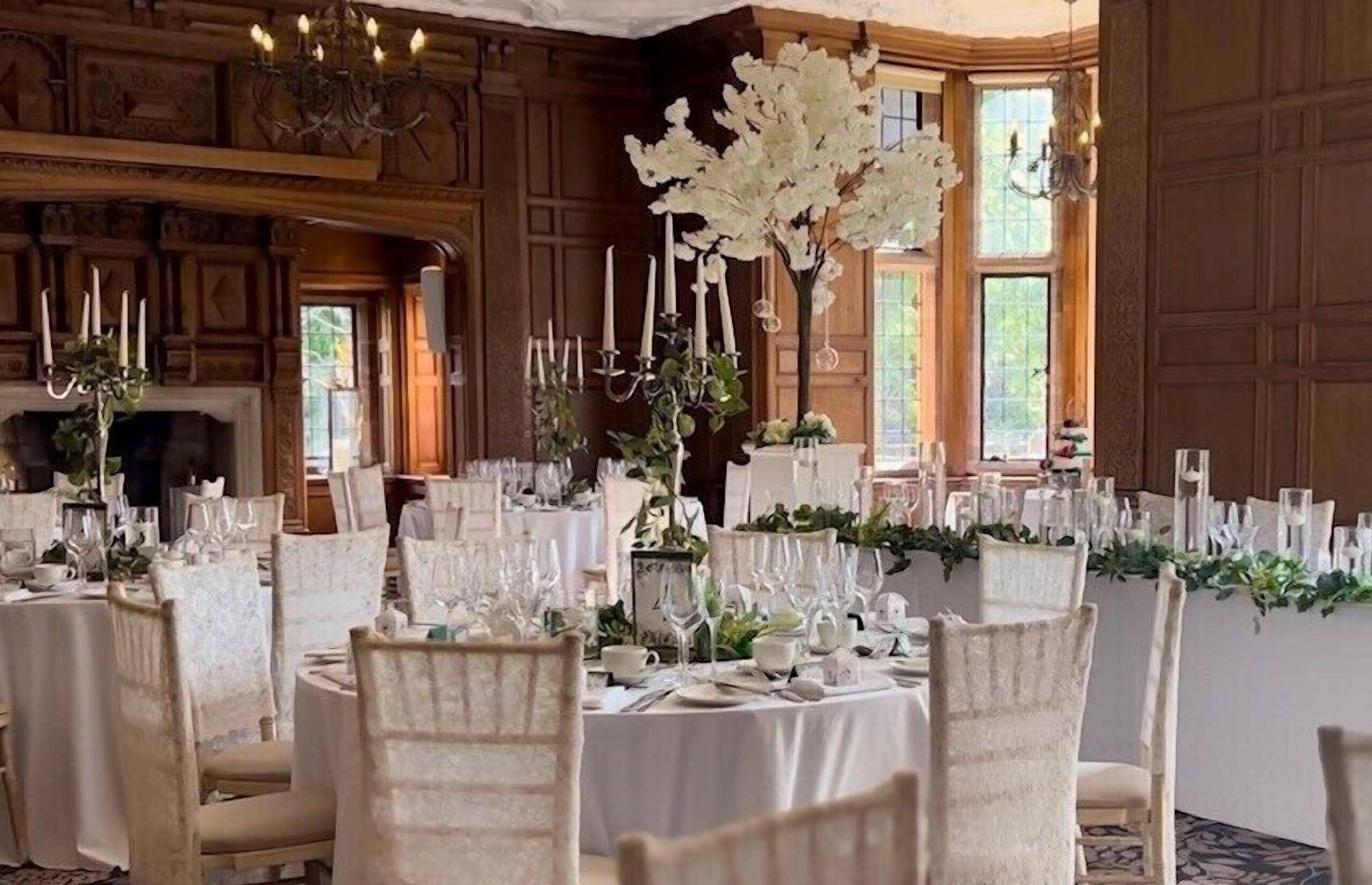 A formal dining room with round tables, white tablecloths, and floral centerpieces.