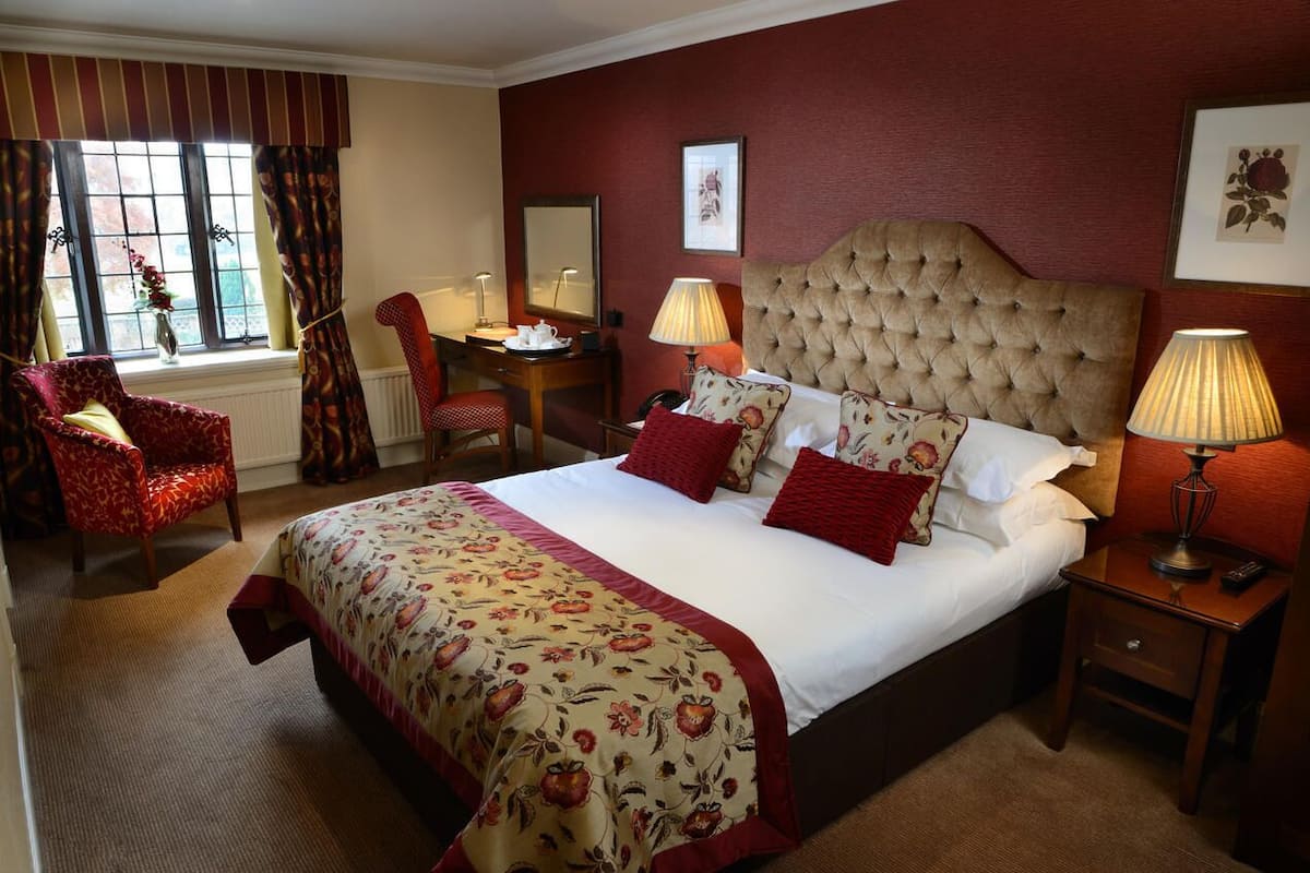A hotel room with a large bed, a desk, and a chair.