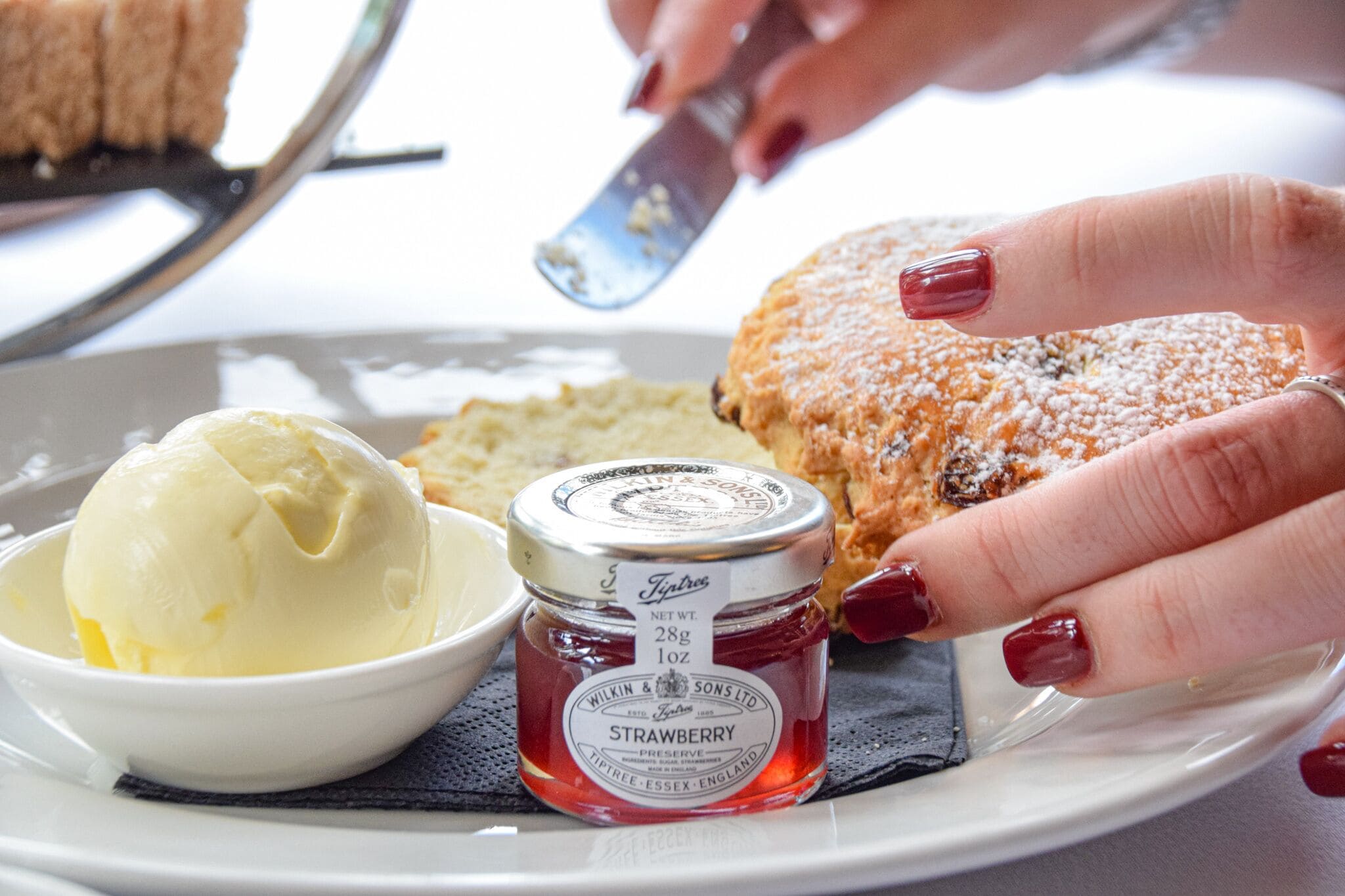 A plate with a scoop of ice cream, a pastry, and a jar of strawberry preserve.