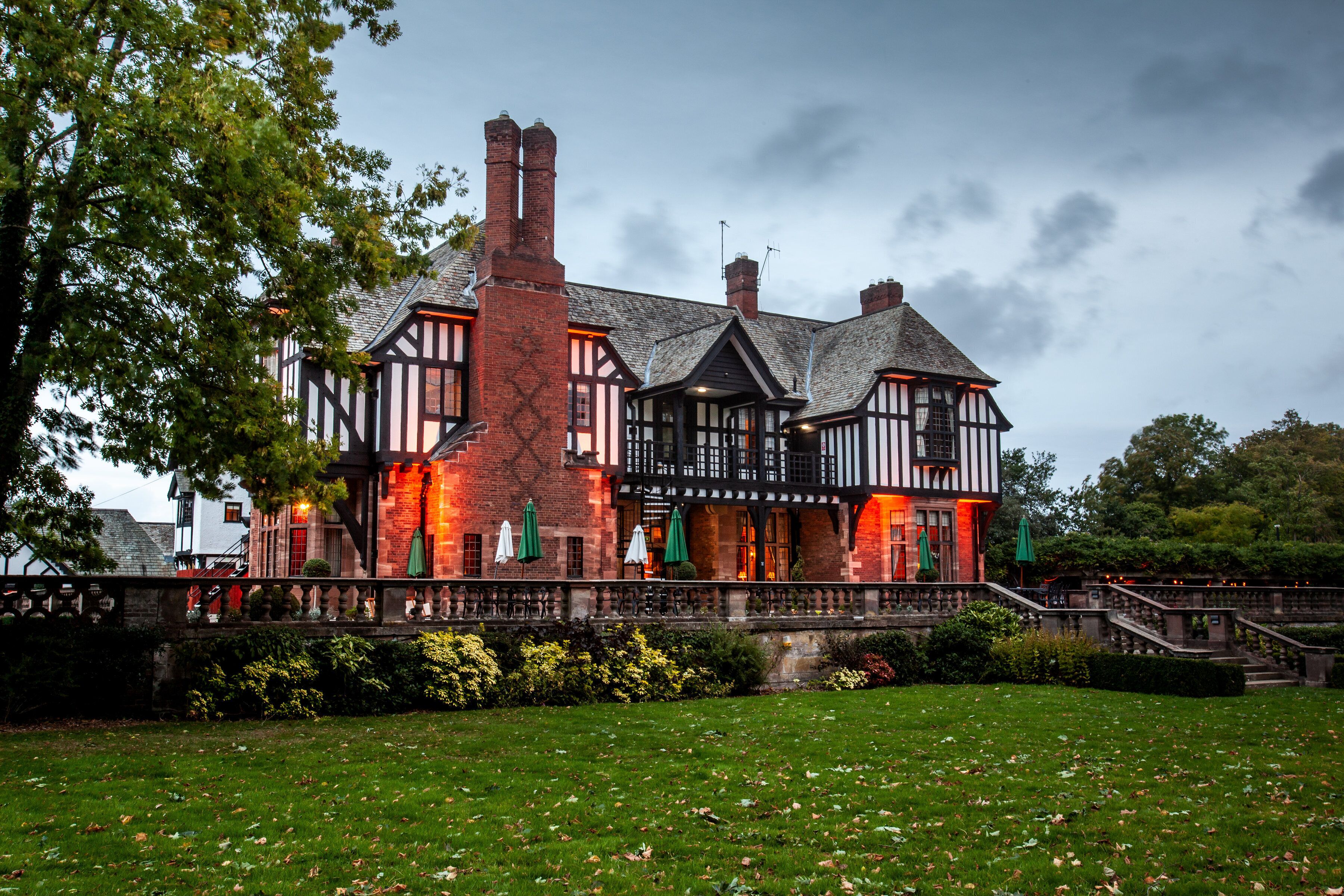 Un bâtiment de style Tudor, avec une façade en briques, de nombreuses cheminées et un balcon agrémenté de parasols.