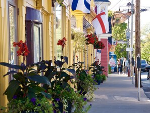 A street with buildings, flags, and pedestrians.