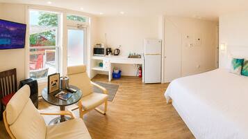 Een hotelkamer met een bed, een eettafel met stoelen, een kitchenette, een televisie en uitzicht op het omliggende gebied.
