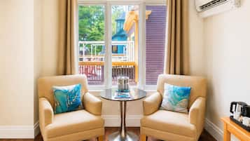 A room with two beige armchairs, a small round table, and a view of a colorful building outside.