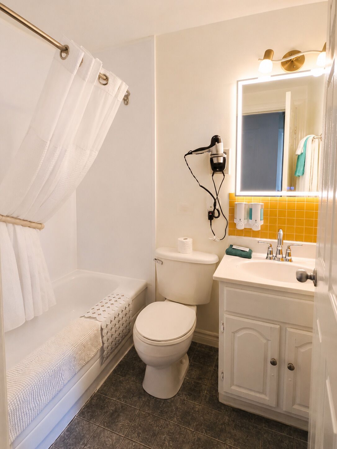 A bathroom with a shower, toilet, sink, and mirror.