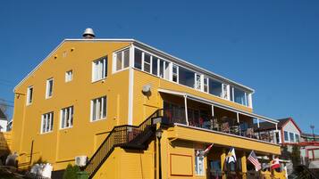 A yellow two-story building with a balcony, a staircase, and a flag.