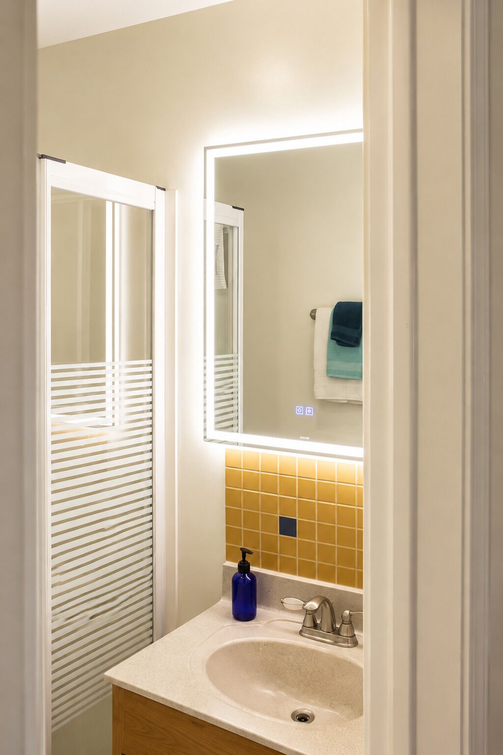 A bathroom with a mirror, sink, and towel rack.