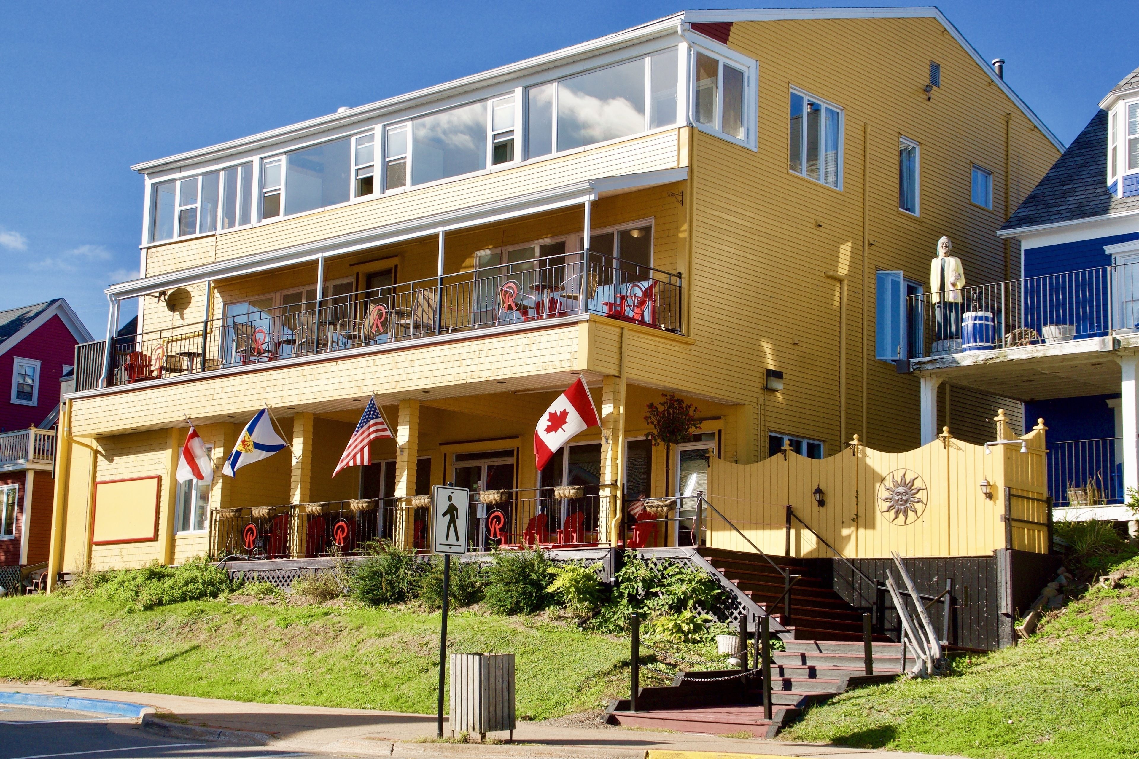 A two-story building with a balcony, a Canadian flag, and an American flag.