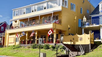 Un edificio de dos pisos con un balcón, una bandera canadiense y una bandera estadounidense.