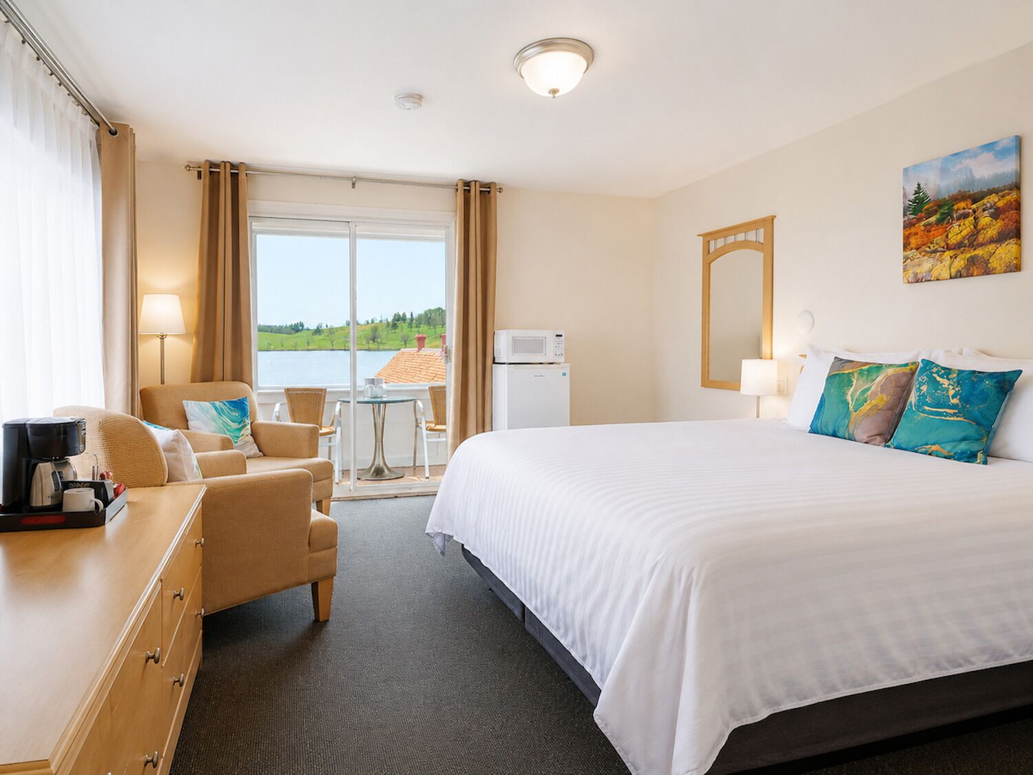 Quarto de hotel com cama, escrivaninha, cadeira, mesa pequena, micro-ondas e vista para o exterior.