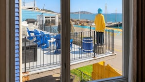 A balcony with a view of a beach, a pool, and a statue. - Rum Runner Inn (Lunenburg)