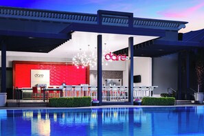 Un hotel moderno con una decoración en rojo y blanco, piscina y zona de estar al aire libre.