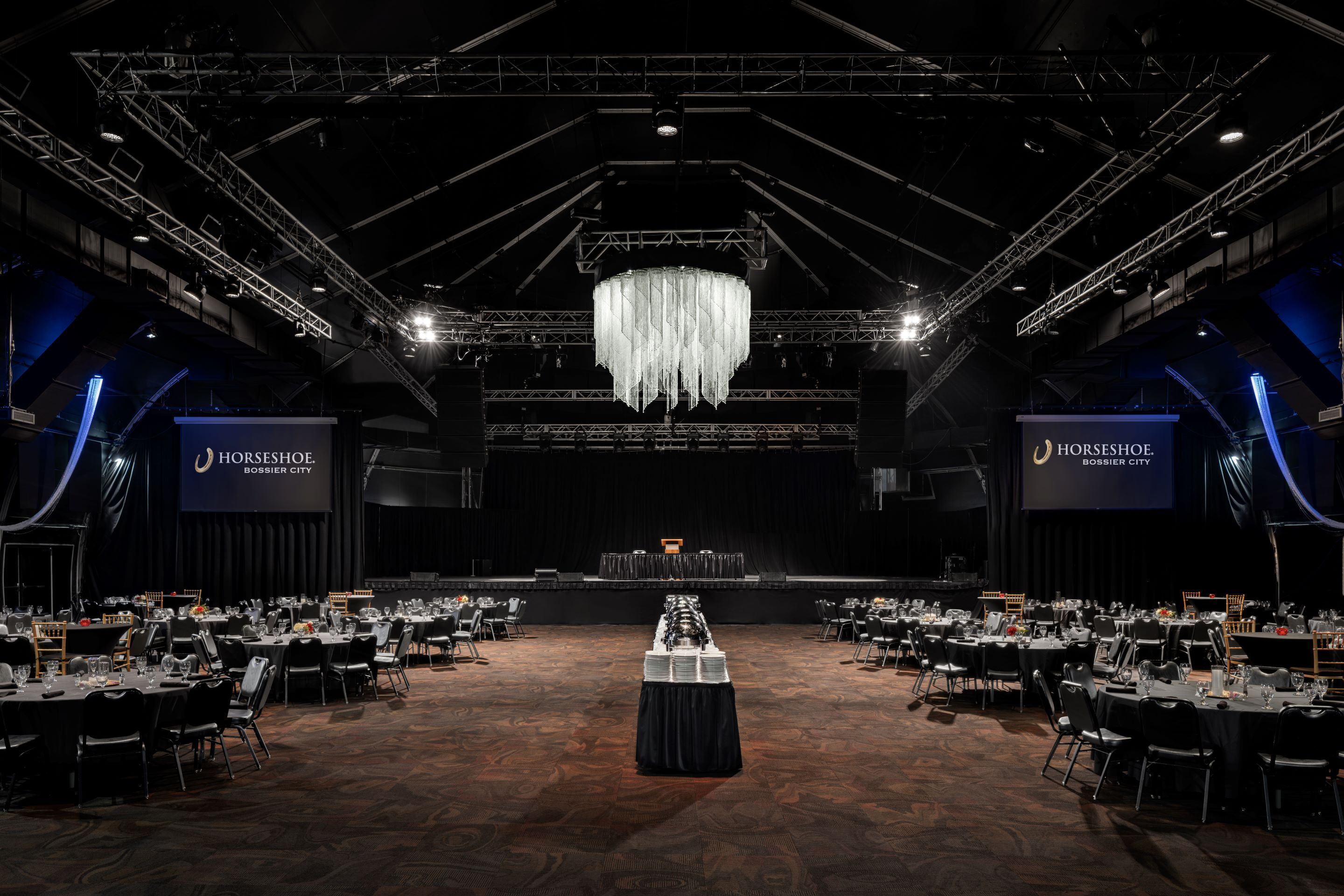 A large conference room with rows of tables, a chandelier, and banners for 'Horseshoe Bossier City'.