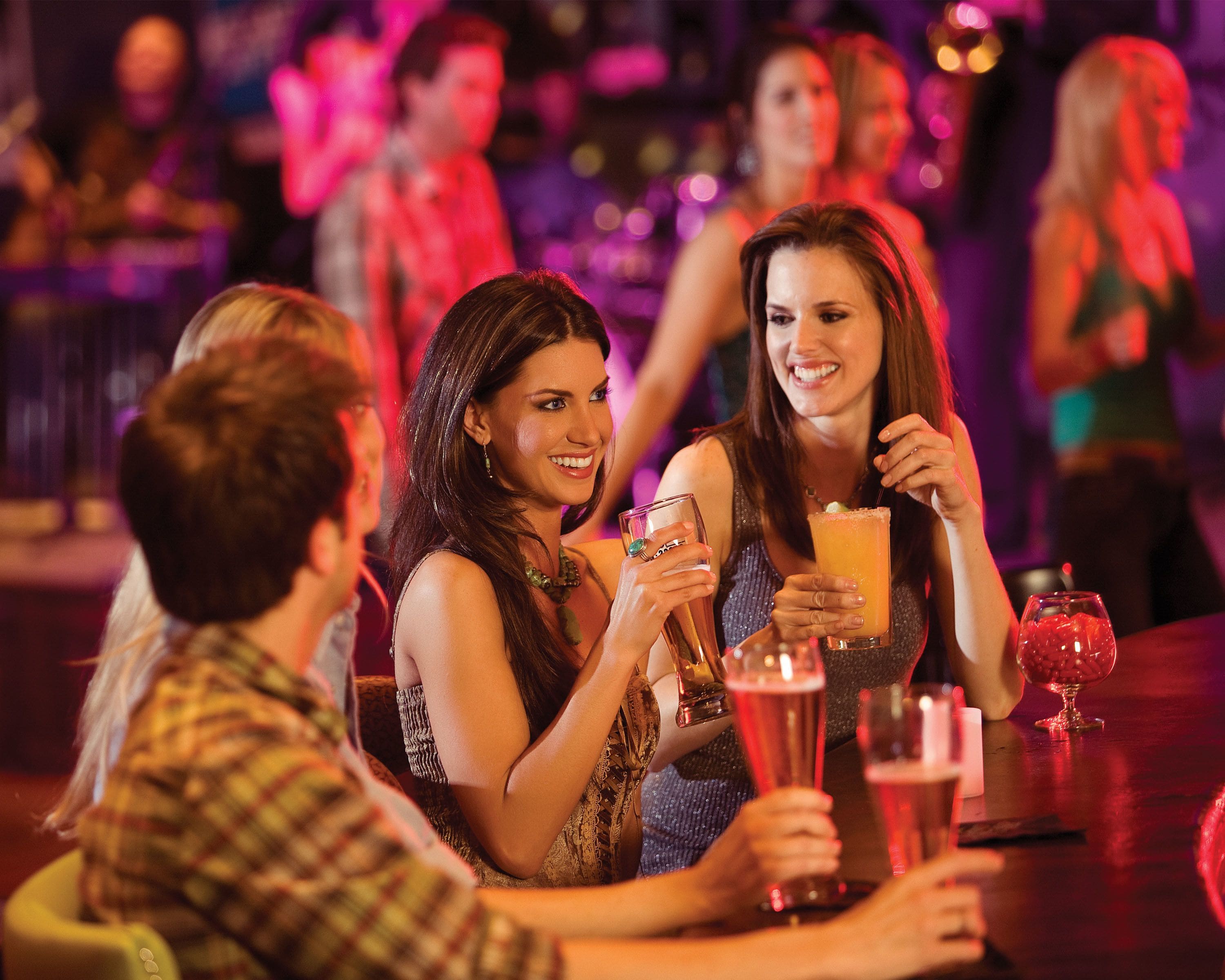 A group of people seated at a bar with drinks, suggesting a social setting.