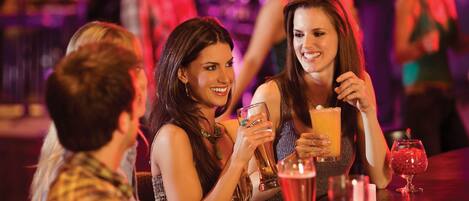 Un grupo de personas sentadas en una barra con bebidas, creando un ambiente social.