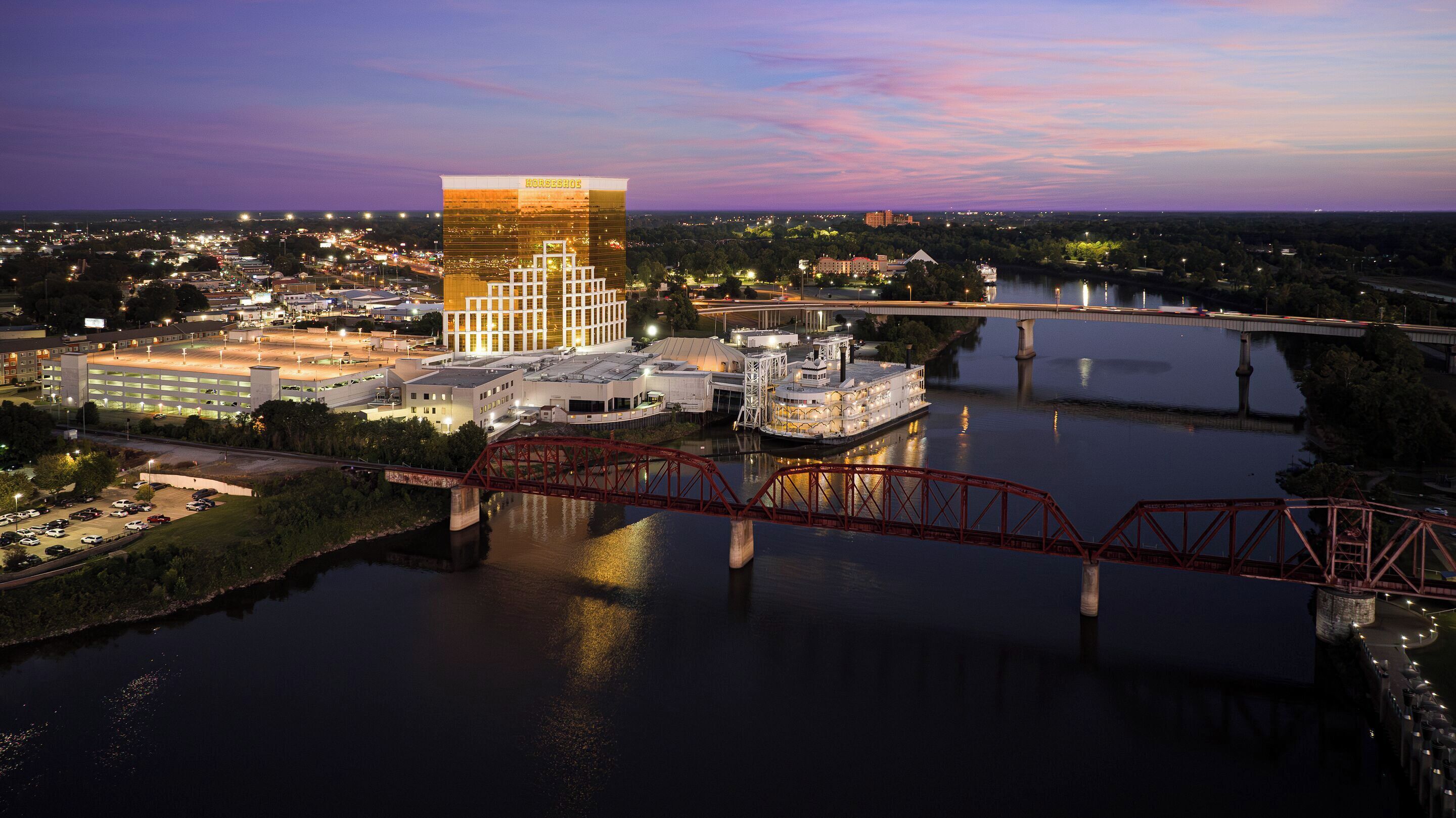 Um hotel grande com um edifício em formato de ferradura, um rio e uma ponte.