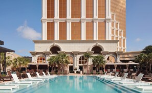 Ein Hotel mit großem Pool, Liegestühlen und Palmen.