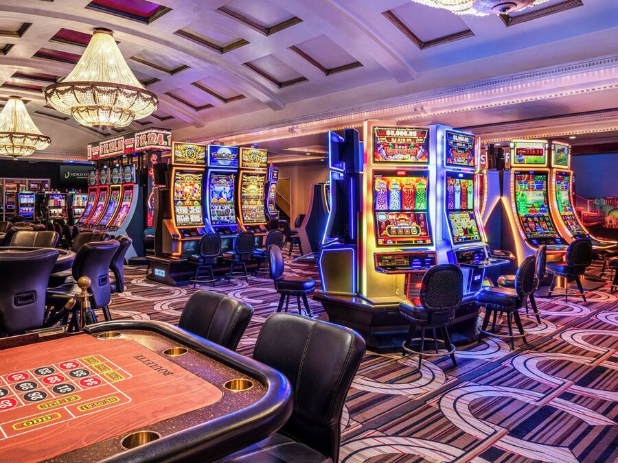 Ein Casino mit Spielautomaten, Blackjack-Tischen und einer Kristallleuchtre.'