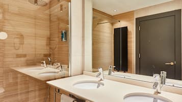 A modern bathroom with two sinks, a large mirror, and a shower.