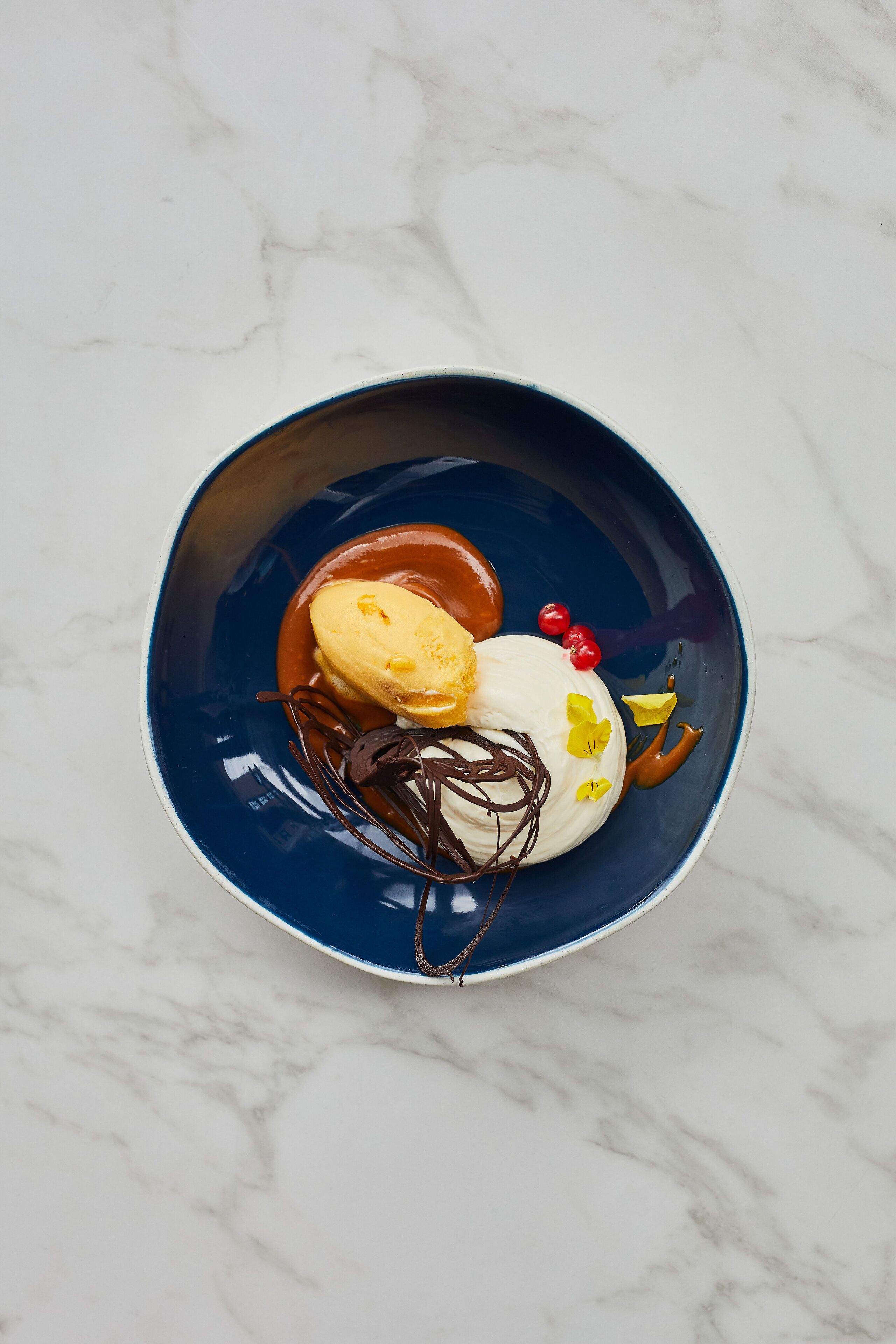 Un postre sobre un plato azul, con un fondo de mármol.