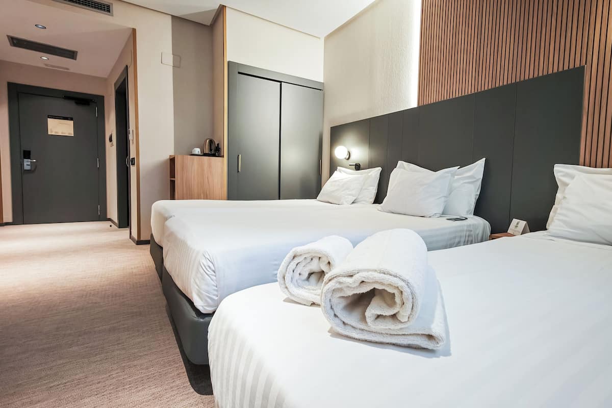 Ein Hotelzimmer mit zwei Betten, einer Holzwand und einer Minibar.